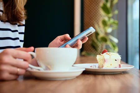 Woman hand use smartphone at cafe, surfing internet browser, have a coffee break. Online...