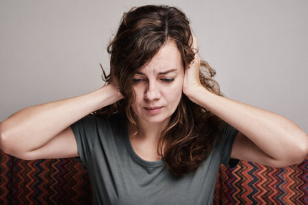 Woman covered her ears with hands, have strong headache, exhausted and stressed person in depressionの写真素材