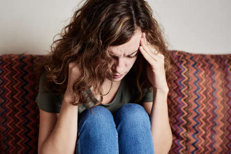 Woman at home feeling strong headache, touching her temples, migraine due to stress and mental...