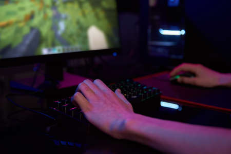 Professional gamer play computer video game in dark room, use neon colored rgb mechanical keyboard, place for cybersport gamingの写真素材