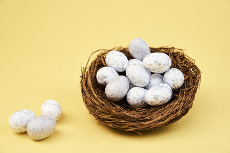 Nest with small eggs on yellow background, Happy Easter card