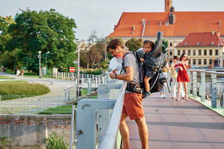 Man carry child while walking at city street. Wroclaw, Poland - August 13, 2021のeditorial素材
