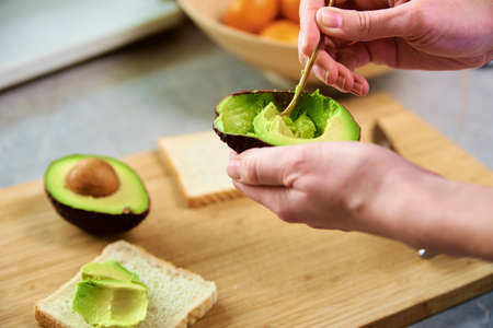 Woman hold fresh ripe avocado and peeling it with spoon, Healthy food and dieting concept, Organic...