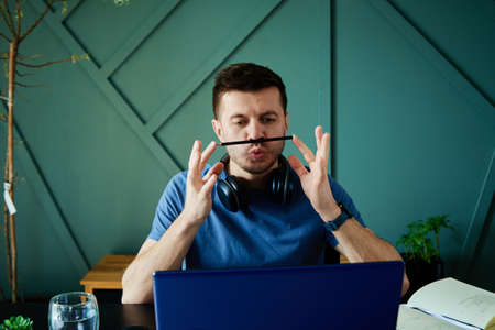 Unproductive lazy man have fun in workplace at home, Male freelancer procrastinating at remote workの写真素材