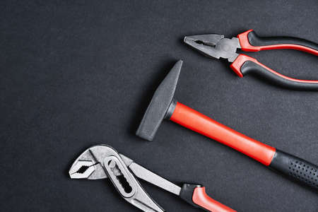 Set of renovation tools. Instruments for repair and maintenance. Hammer, wrench and tongs on black background, top view flat layの写真素材