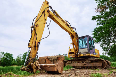Yellow excavator on construction site, Heavy construction machine excavating soil, Crawler backhoe...