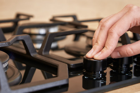 Female hand adjusting temperature on gas hob control panel, Woman using gas stove, Modern household appliancesの写真素材