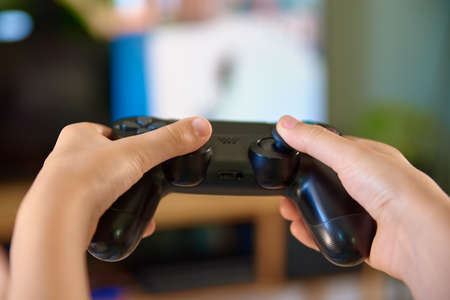 Boy playing video game on console with joyctick gamepad in his hand, Online entertainment and...