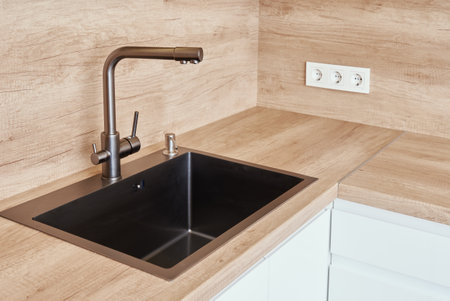 Black stainless sink with tap in kitchen interiorの写真素材