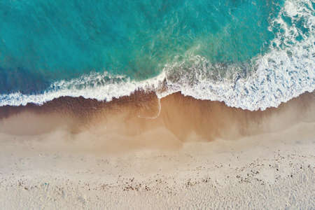 Sand beach with sea waves, top view. Summer vacation and travel concept. Beautiful coastline with...