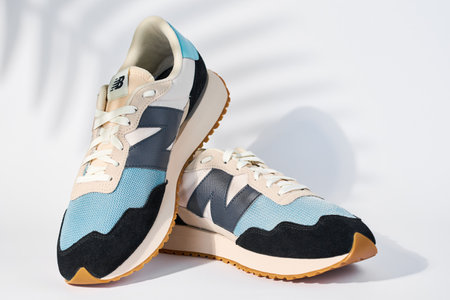 Stylish New Balance brand shoes model MS237HL1 on white background with plant shadows, Trendy...