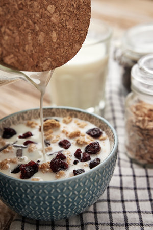Granola with milk in blue bowl on wooden table, Healthy organic breakfast with muesli, Food clean...