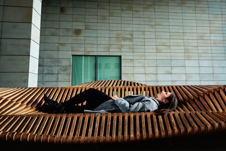 Stylish pretty woman lying on bench at city street. Woman resting at summer day outdoorsの写真素材