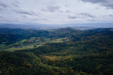 Drone flight over mountains covered with forest at autumn season. Mountain village, aerial view. Beautiful nature landscapeの写真素材