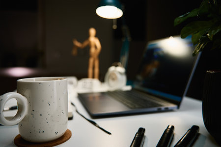 Workplace at home office with laptop, cup of coffee and lamp on desk for working at nightの写真素材