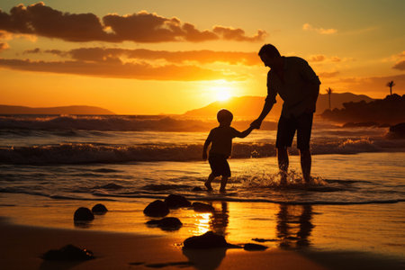 Father and son silhouettes walking at sunset beach together. Happy relationships in familyの素材