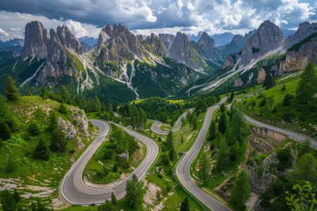 Serpentine mountain road winding through lush green forest. Aerial panoramic view of curvy mountain road.の素材