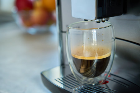 Fresh espresso at morning. Coffee machine in kitchen, close up. Modern coffee maker with freshly brewed coffee in glass cup. Kitchen appliancesの写真素材