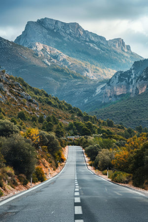Empty road leading towards mountains under a dynamic sky. Beautiful landscape with highway and mountain rangesの素材