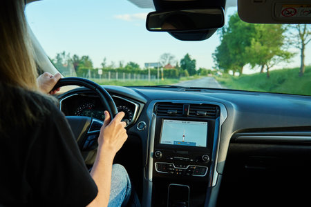 Woman driving car on country road at sunset. Back view of female driver in vehicleの写真素材