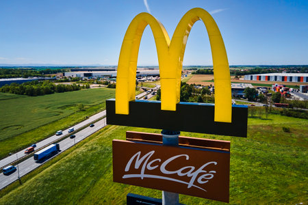 Aerial view of Mcdonalds McCafe sign stands near busy highway with clear blue sky and agriculture fields in background. McDonalds restaurant. Katy Wroclawskie, Poland - May 14, 2024のeditorial素材