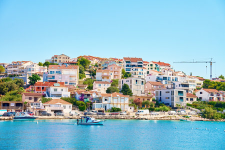 Seaside town with colorful coastal houses on hillside with boats docked along clear blue waters....