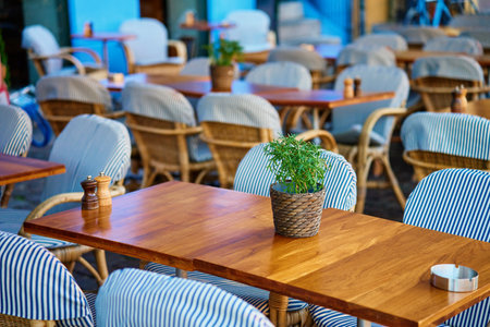 Street cafe in morning. Empty outdoor patio with chairs and potted plants on table. Terrace with tables waiting for visitors in European cityの写真素材