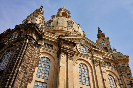 Buiilding exterior of Dresden Frauenkirche. Baroque architecture with stonework, large arched windows and grand dome under a clear skyの写真素材