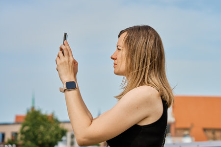 Woman taking photos of historical buildings in European city. Female tourist captures memories...