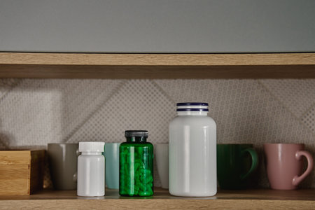 Kitchen cabinet with medical containers, pills and vitamins on shelf. Taking pills or vitamins for health careの写真素材
