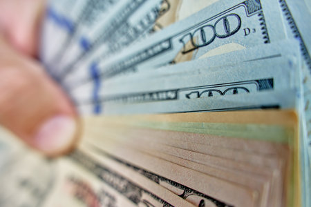 Close-up of hands counting stack of dollar bills. Man holding american dollars cash. Concept of cash management, wealth or financial transactionsの写真素材