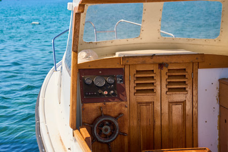 Wooden cockpit of small boat with steering wheel, gauges and cabin interior. Touristic yacht in seaの写真素材