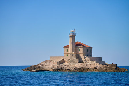 Sea landscape with lighthouse on tall rocky island in sea on sunny dayの写真素材