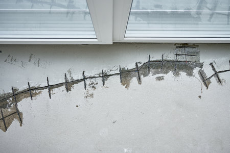 Repairing cracks in concrete floor near window using sealant. Renovation process in house under...