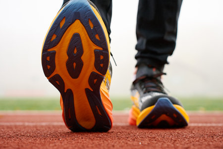 Close-up of running shoes sole with athlete training at stadium. Sportsman legs in sport sneakers on track surfaceの写真素材