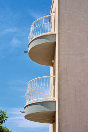 Modern building facade with simple curved balconies against blue sky. Minimalistic architectural designの写真素材