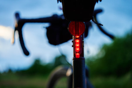 Glowing bicycle tail light in twilight. Red stop light for cyclist visibility and safety during...
