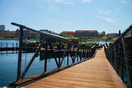Wooden walkway with railings leading to stylish restaurant on city embankmentの写真素材