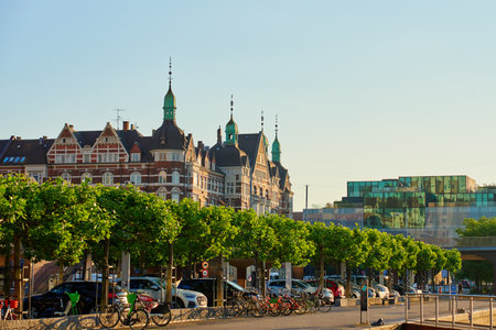 Copenhagen cityscape with modern buildings and historical architecture on sunny day. Row of trees...