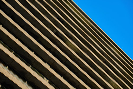 Contemporary architectural design with repeating geometric balconies against clear blue sky....