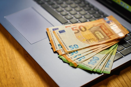 Euro banknotes on laptop keyboard. Concept of cash money, digital payments and financial transactionsの写真素材