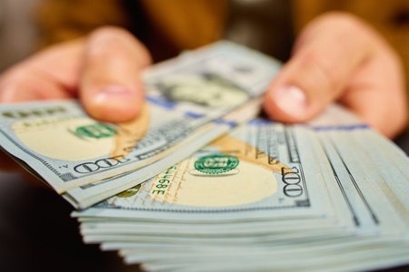 Man counting US dollar banknotes, close up. Cash savings and financial wealth concept