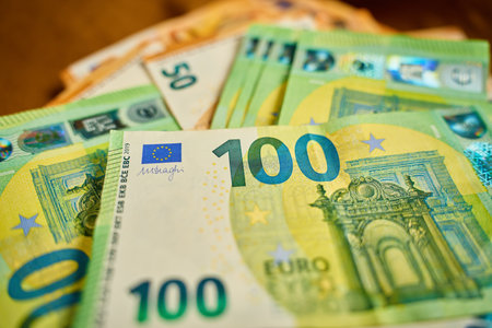 Close-up of euro banknotes stacked on brown fabric surface. Concept of cash transactions, finance, banking and businessの写真素材