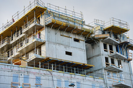 Unfinished high-rise building with concrete walls and scaffolding. Urban construction project in...