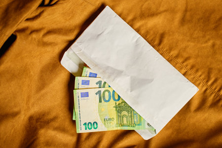 Envelope filled with euro banknotes, top view. Close-up of money cash on brown background. Concept...