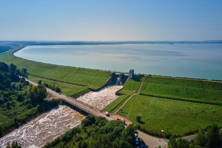 Aerial view of large dam discharging water into channel, managing water levels in reservoir, releasing water through floodgates. Mietkow, Polandの写真素材