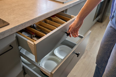 Person opens a kitchen drawer with various utensils in wooden cutlery tray. Woman opening kitchen...