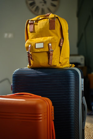 Yellow backpack and two suitcases ready for travel. Packed luggage in living room. Concept of vacation and preparing for departureの写真素材