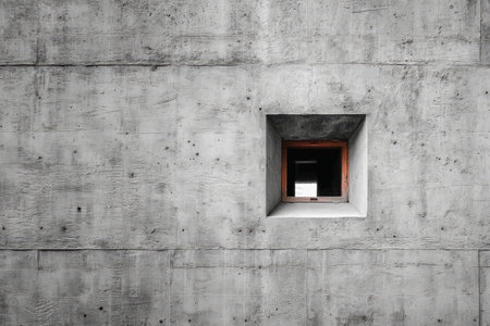 Concrete wall with square window as minimalist architectural element. Detail of urban design, geometry and contemporary structureの素材