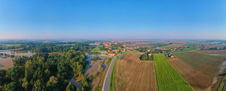 Panoramic aerial view of flooded areas near rural village, surrounded by green fields and farmlands. Countryside landscapeの写真素材